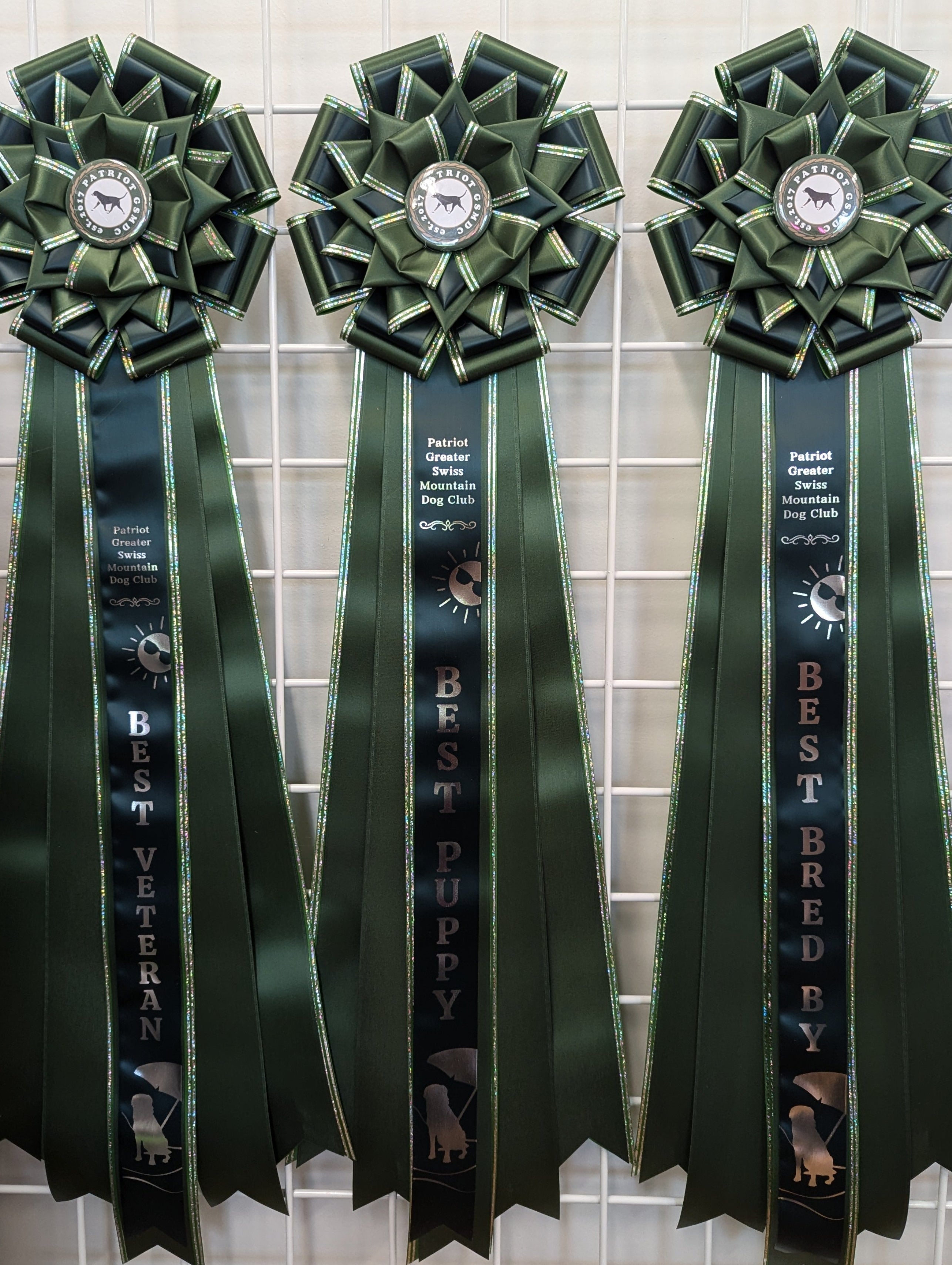 Three green ribbons with awards on a tiled wall